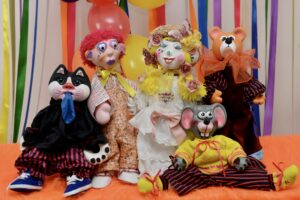 Groupe de marionnettes créées par Sylvette Pagan comprenant deux personnages, un chat, une souris et un ours, installés comme pour une photo de famille.